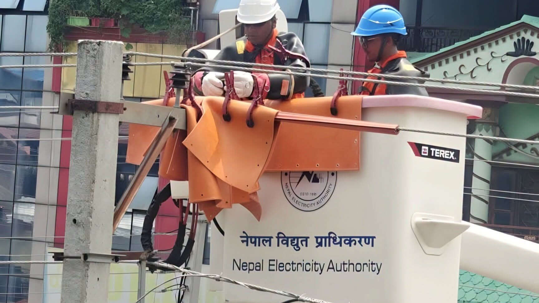 नेपाल विद्युत प्राधिकरणका प्राविधिकहरू सुरक्षा उपकरणसहित बकेट लिफ्ट प्रयोग गर्दै उच्च भोल्टेज विद्युत लाइनमा मर्मत कार्य गरिरहेको दृश्य।