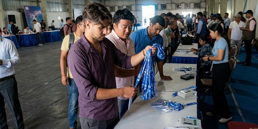 काठमाडौँमा बन्द सत्रका लागि प्रतिनिधिहरूलाई परिचयपत्र वितरण गर्दै कर्मचारी र सहभागीहरू भीडभाड भएको हलमा देखिएका छन्