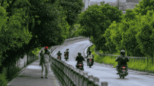 ललितपुरको सानेपा रिङ रोडमा हरिया रुख, घुमाउरो सडक, मोटरसाइकल चालक र फुटपाथमा हिँडिरहेका पैदलयात्री।
