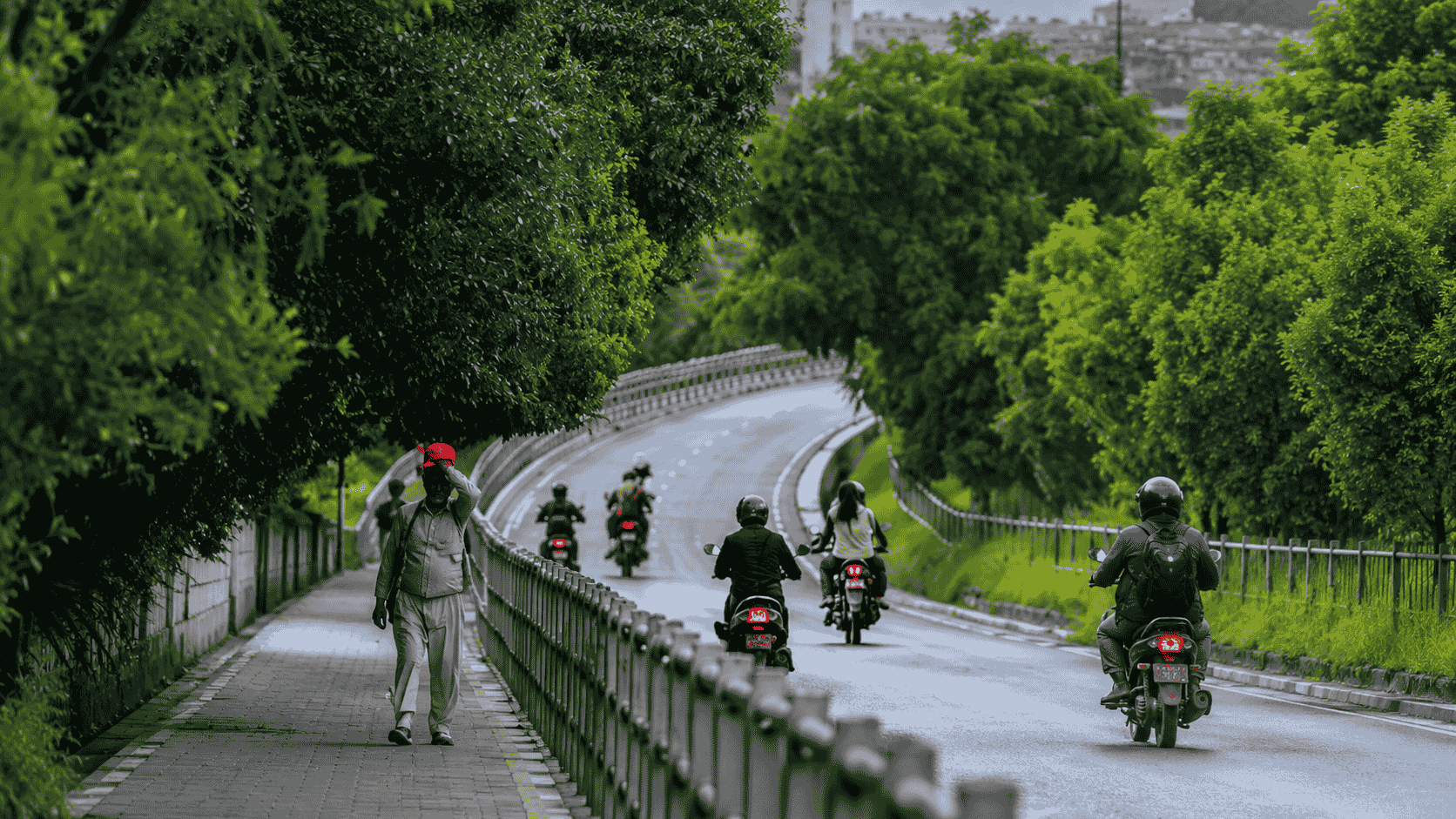ललितपुरको सानेपा रिङ रोडमा हरिया रुख, घुमाउरो सडक, मोटरसाइकल चालक र फुटपाथमा हिँडिरहेका पैदलयात्री।