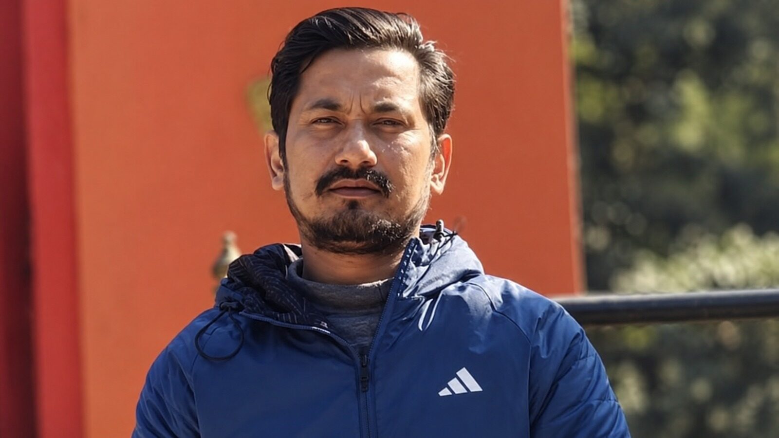 निलो ज्याकेट लगाएका एक पुरुष बाहिरी स्थानमा उभिएको दृश्य