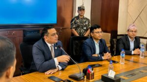 औपचारिक बैठकमा टेबल वरिपरि बसेका सरकारी अधिकारीहरू र छलफल गर्दै गरेको दृश्य